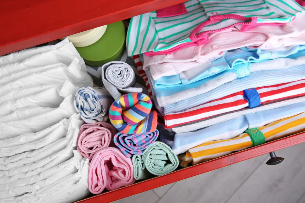 Chest of drawers with clothes and diapers in baby room